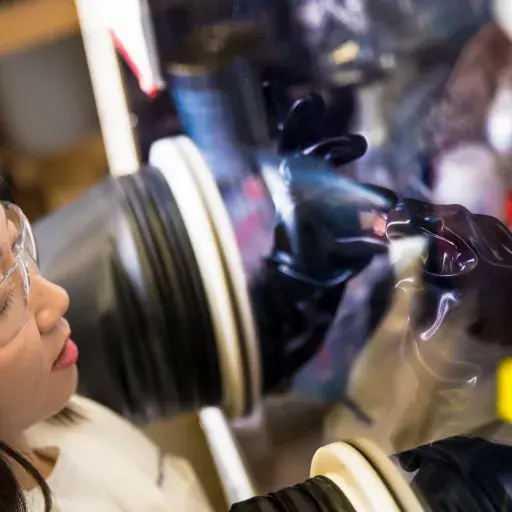 A girl working in a lab with protective glasses and gloves