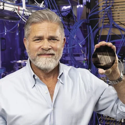 Ray Smets holding a quantum circuit and smiling at the camera