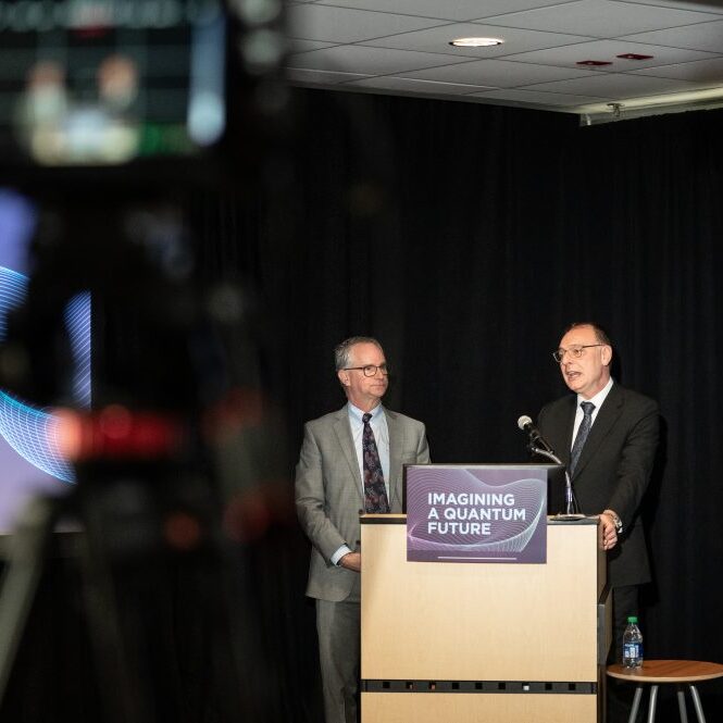 Two men speaking into a microphone